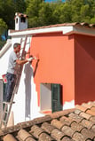 a man is painting a house with a ladder