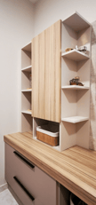 Salle de bains avec plan bois clair, portes anti trace de doigts, élément déco beige posé sur plan.