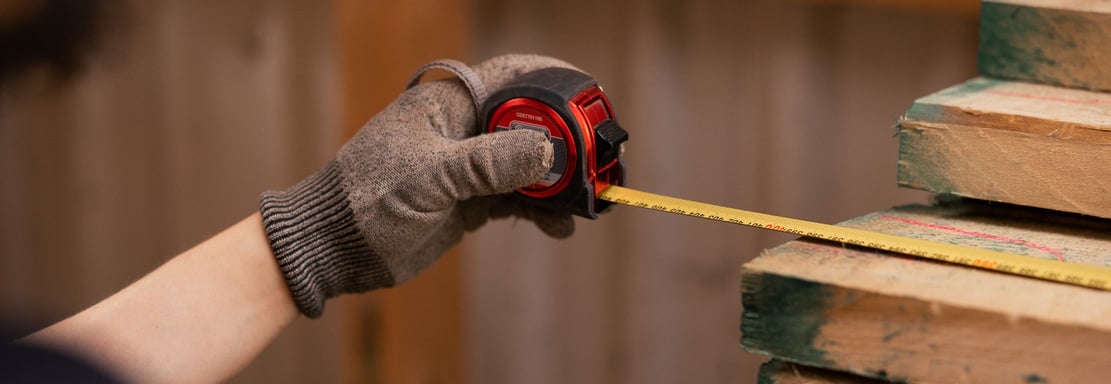 a person holding a tape measure ruler and measuring tape measure tape on wood wood plank