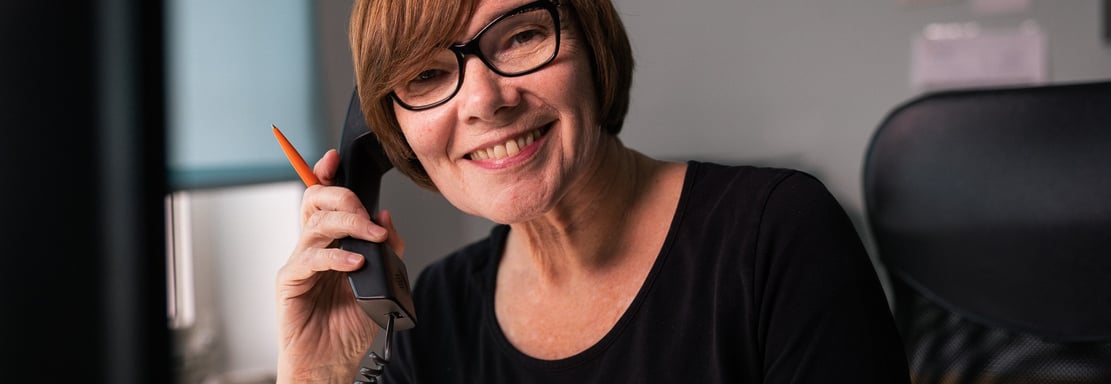 eine frau mit braunen haaren und brille spricht in ein telfon im atelier rohlfs