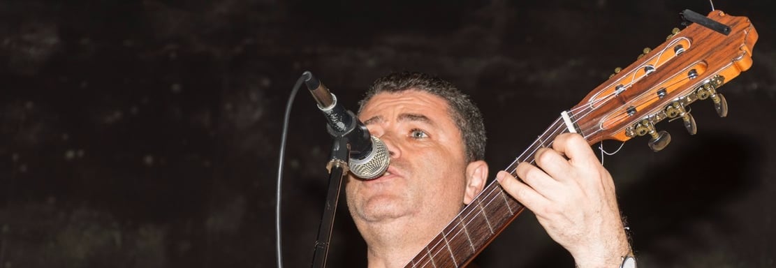 a man with a guitar and microphone in front of a microphone