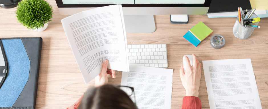 a woman sitting at a desk with a book and a computer