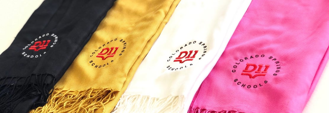 Custom embroidered graduation stoles in black, gold, white, and pink with Colorado Springs Schools l