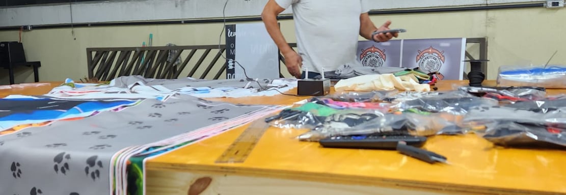 Imagem da mesa de corte da Persona estamparia, com vários materias e produtos sobre a mesma.