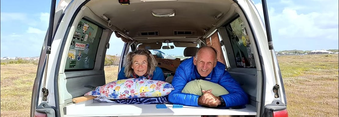 a man and woman in a van with a bed in the back exploring Africa