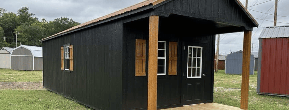 a small black cabin with a wooden deck and a wooden deck