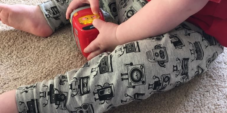 a toddler boy sitting on the floor with a toy wearing robot music robot themed leggings