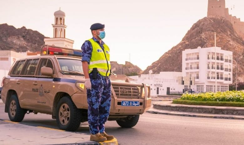 a man in a yellow vest and blue pants standing in front of a car