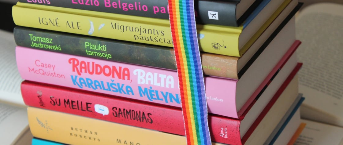 a stack of books with a rainbow - colored ribbon tied to a book