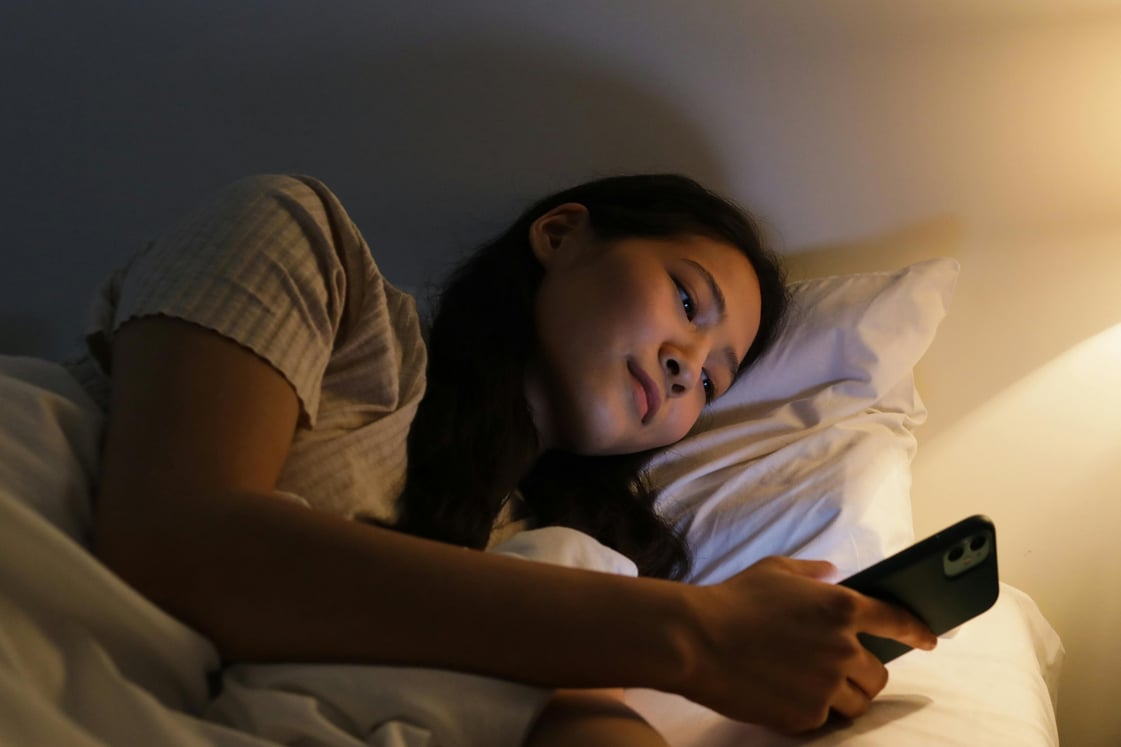 mulher usando celular na cama
