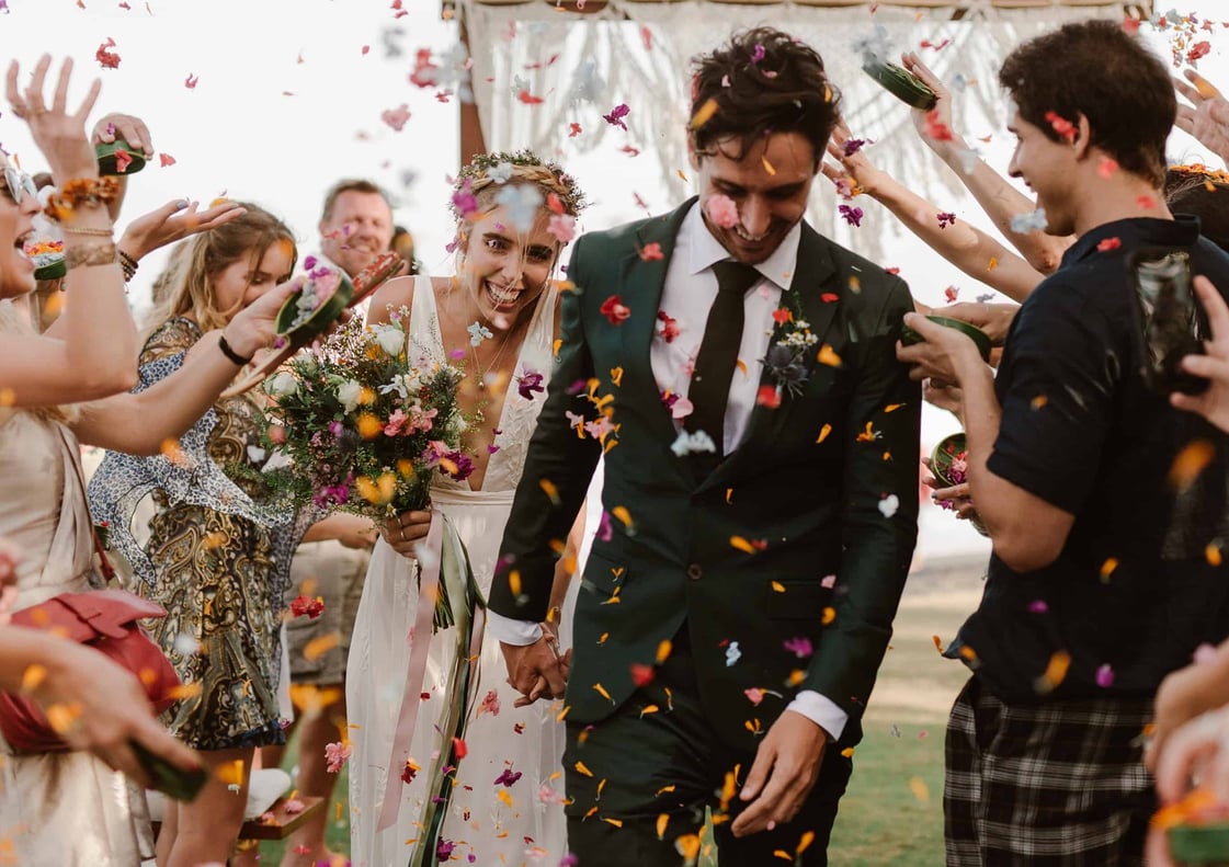 Flowers being thrown on bride and groom as they walk down the aisle