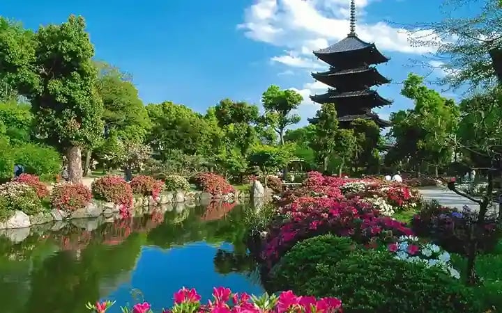 Temple indou au bord d'un bassin d'eau bordé de grands arbres et de fleurs