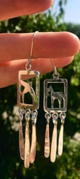a pair of earrings with a horse and a swallow on it