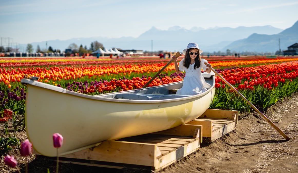 a little girl in a white dress and hat is sitting in a boat