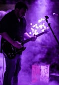 John playing guitar with purple smokey background