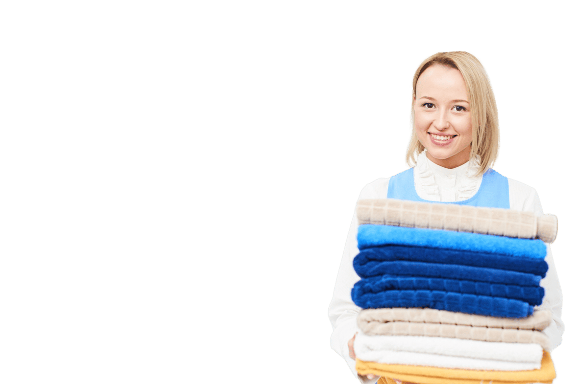 a woman holding a stack of towels in commercial laundry.