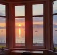 The window at Gourock Seaview Holiday Let with a view of the sun setting over the water