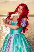 Ariel de La Petite Sirène dans un cosplay, tenant ses cheveux dans un geste féminin et gracieux