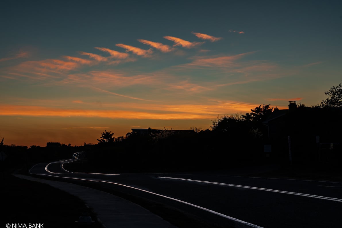 a  dark sunset scene of a road with a car on the horizon, old montauk highway