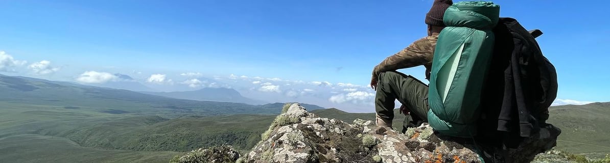 a man sitting on a rock with a backpack on top of it