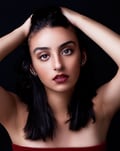 a beautiful brown eyed girl with tanned skin, plump auburn lips, pulling her hair back and posing like a model