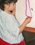 a young girl is holding a piece of paper and a pencil