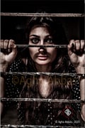 beautiful young girl captive behind bars, with eyes wide open in hope.