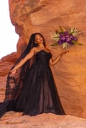 a woman in a black dress and veil holding a bouquet