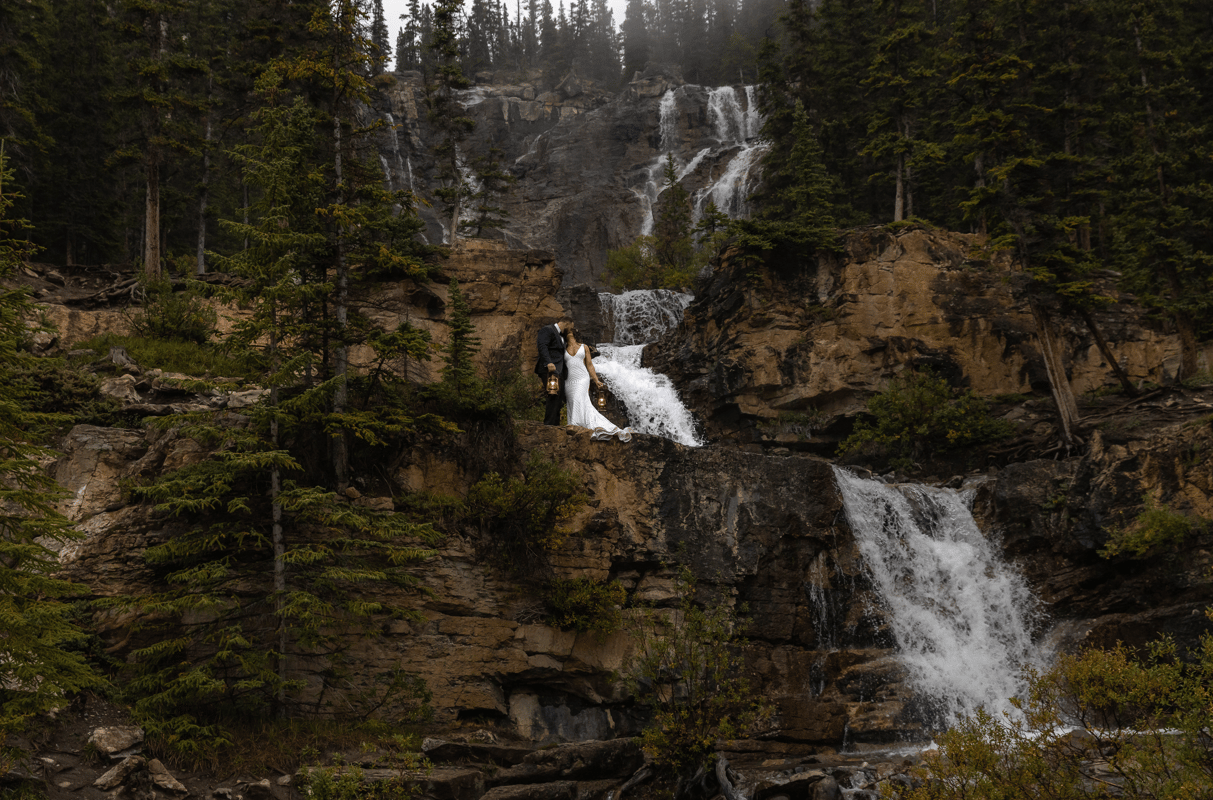 Bride and groom standing on a waterfall in Banff National Park