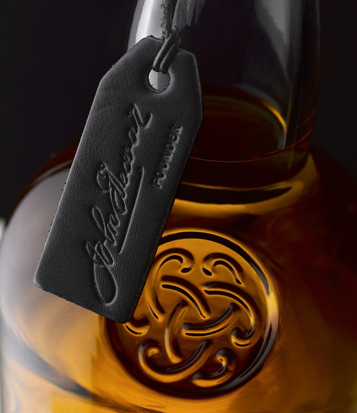 Close up of black leather tag on neck of Dewars whiskey bottle