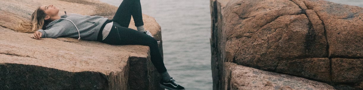 Exhausted young woman lying on the rock. What is fatigue? Mindletic Blog