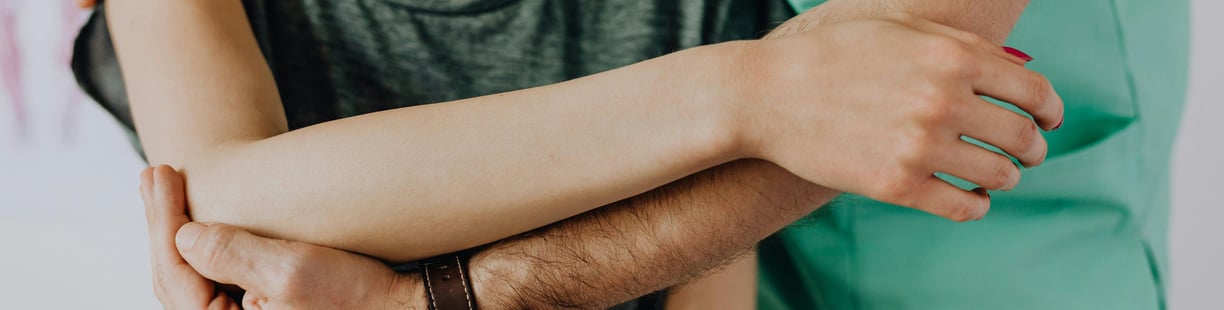 Man supporting woman's arm in treatment.