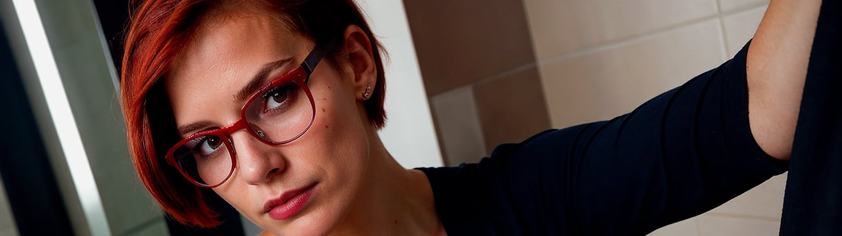 a woman with red hair and glasses on her face