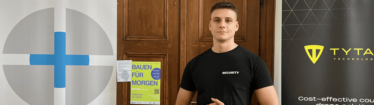 Eine Sicherheitskraft in "SECURITY"- Shirt vor einer Tür