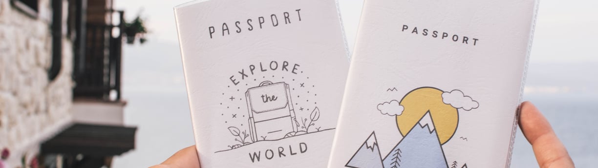 two people holding up their passport cards with a mountain view
