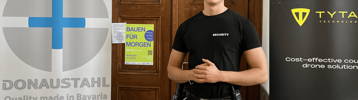 Eine Sicherheitskraft in "SECURITY"- Shirt vor einer Tür