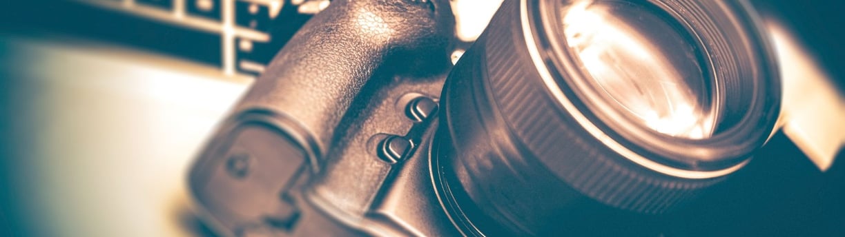 A modern DSLR camera paired with an interchangeable lens, arranged on a sleek surface to highlight learning photography