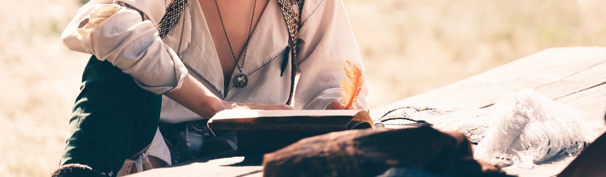 Plan d'une personne en tenue médiévale écrivant dans un livre avec une plume