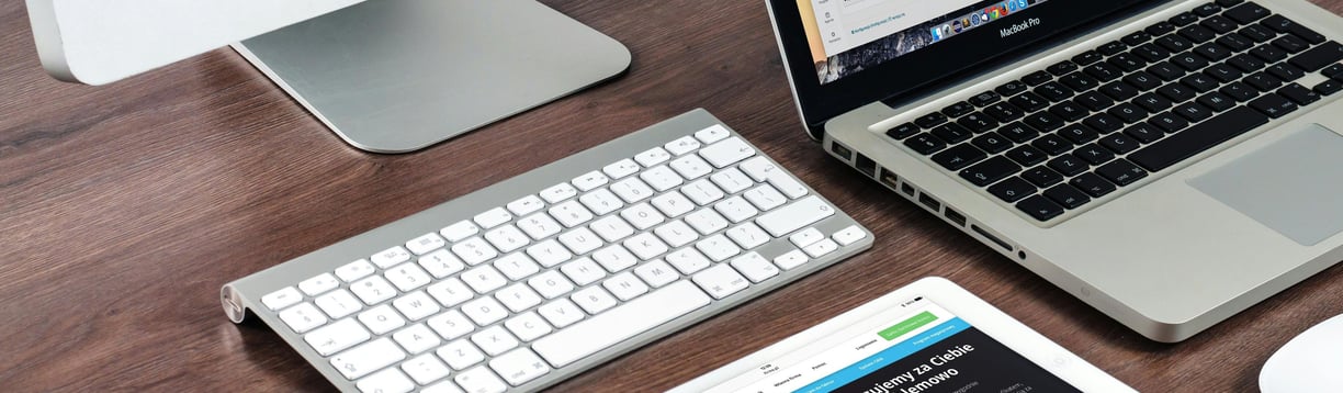 Teclado y portátil sobre escritorio con sitio web abierto, mostrando diseño web profesional.