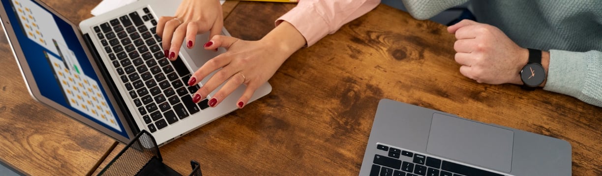 a woman sitting at a desk with a laptop and a man