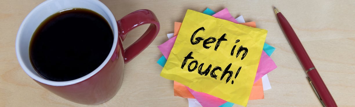 a cup of coffee, pen on a desk and a pile of coloured post-it notes. Top one says Get In Touch