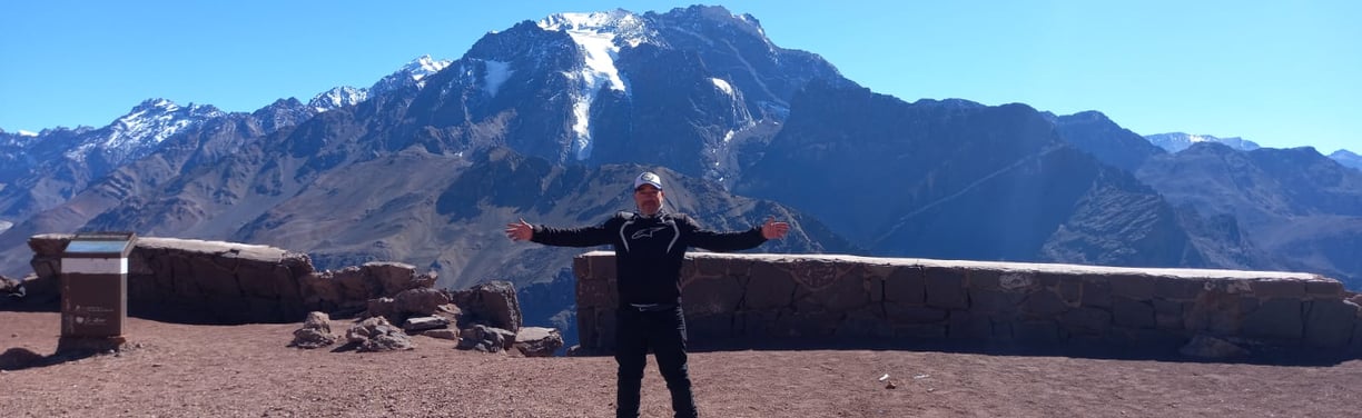 a man standing on a mountain top with his arms outstretched out