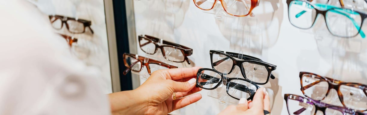 photo de mains opticien qui prend une paire de lunettes en main