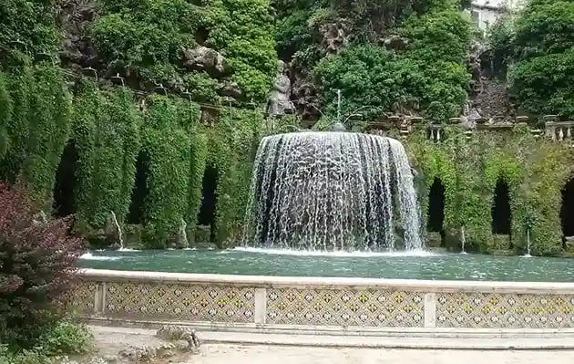 Cascade se jetant dans 1 bassin et entourée de plantes tombantes et de colonnes