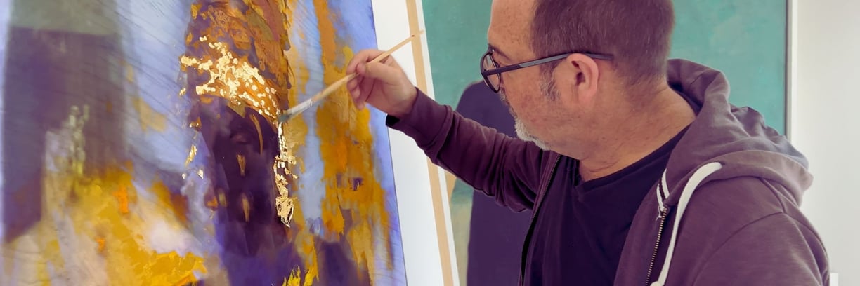 Martin Osner applying gold leaf to a mixed media artwork in his studio