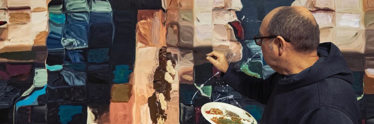 Martin Osner painting a textured mixed media artwork in his studio. He holds a palette of earthy paints an abstract portrait