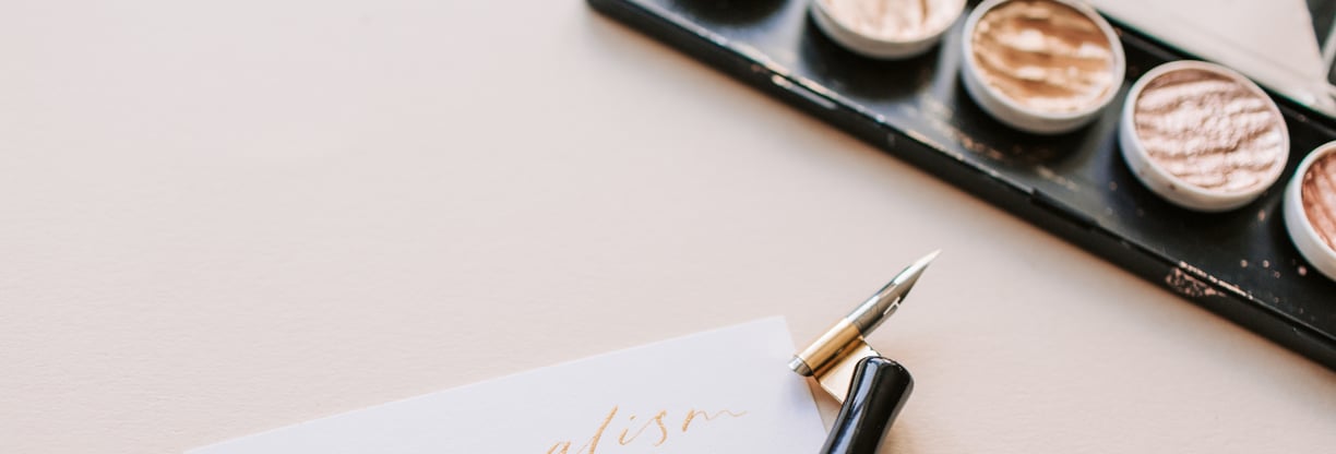 Stylo élégant placé à côté d'une palette de maquillage et d'un carnet.