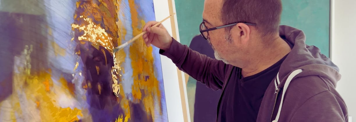 Martin Osner applying gold leaf to a mixed media artwork in his studio