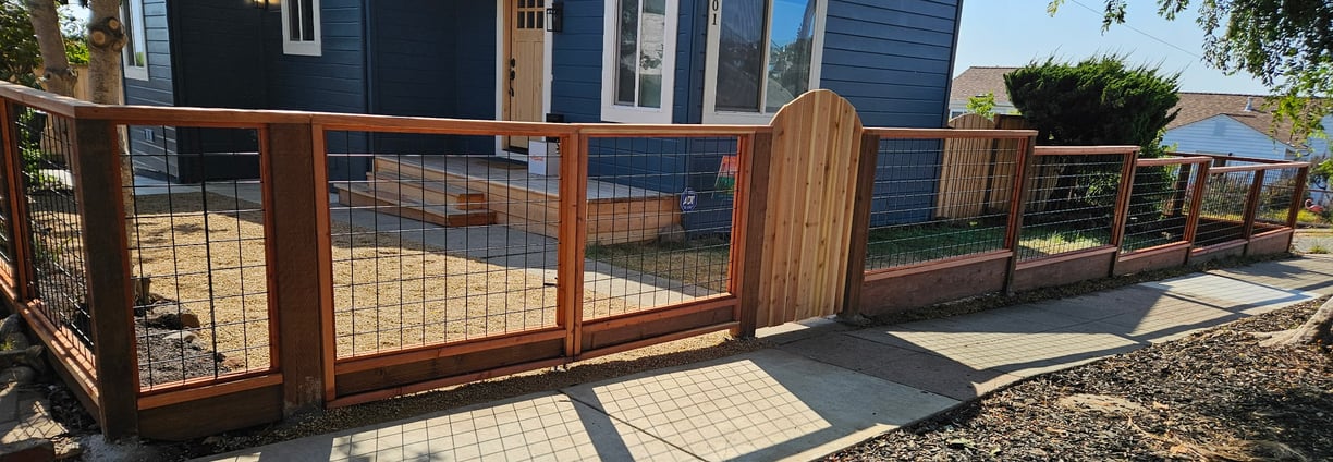 a hogwire fence with a redwood gate