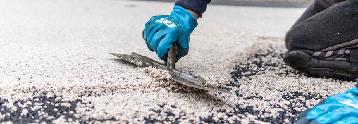 a person wearing gloves and gloves is using a pair of scissors to cut a piece